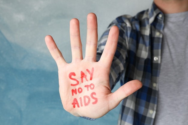 Photo male hand with inscription say no to aids on blue wall, space for text