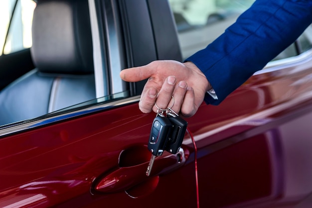 Male hand with keys against new red car