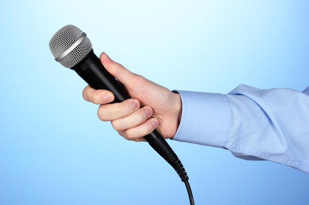 Photo male hand with microphone on blue background