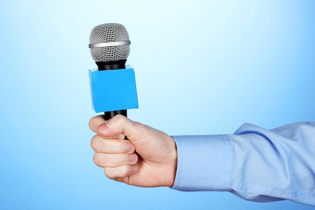 Photo male hand with microphone on blue background