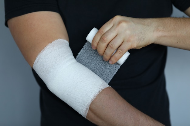 Male hand with tight elastic bandage on elbow closeup