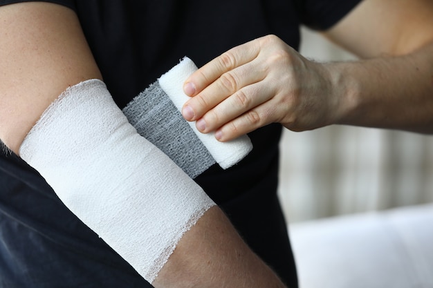 Male hand with tight elastic bandage on elbow closeup