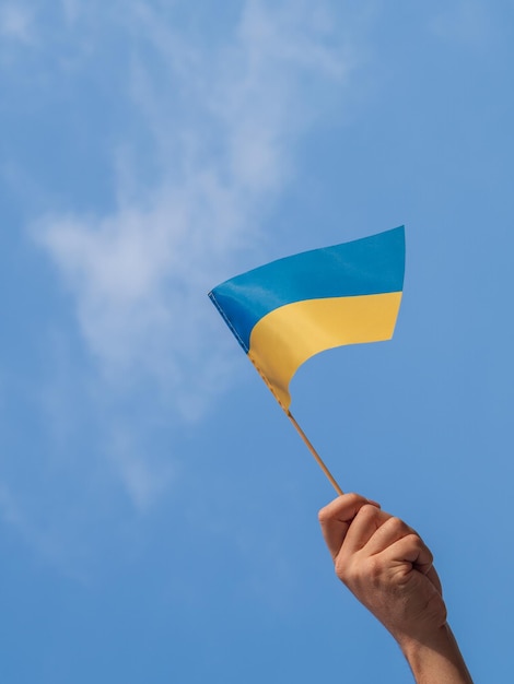 Male hand with ukrainian flag blue sky Protest against russian invasion on Ukraine