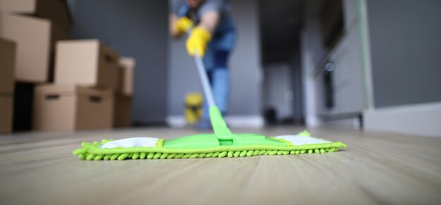 Male hand with yellow protective gloves hold green plastic mop