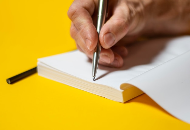 Male hand writing in notebook with pen