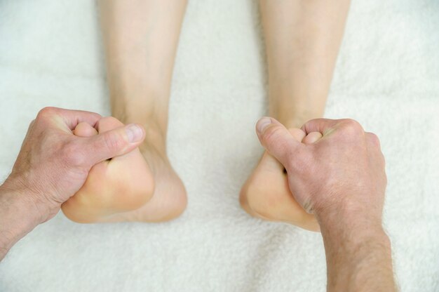 Male hands are massaging feet.