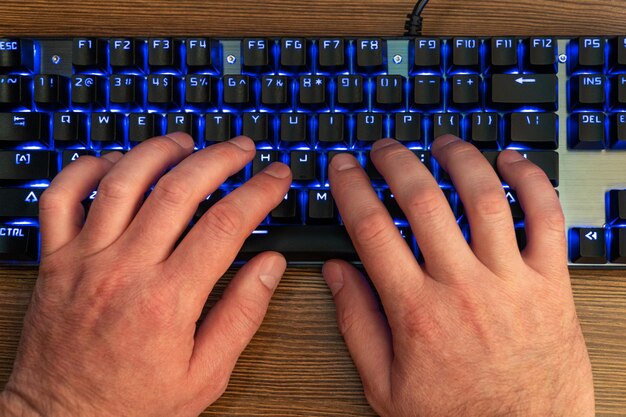 male hands on a black keyboard with blue backlight