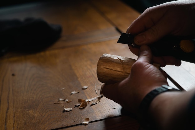 Male hands carve wood with a knife