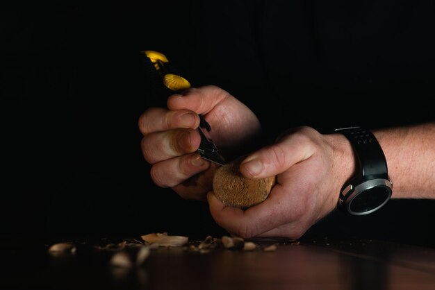 Male hands carve wood with a knife