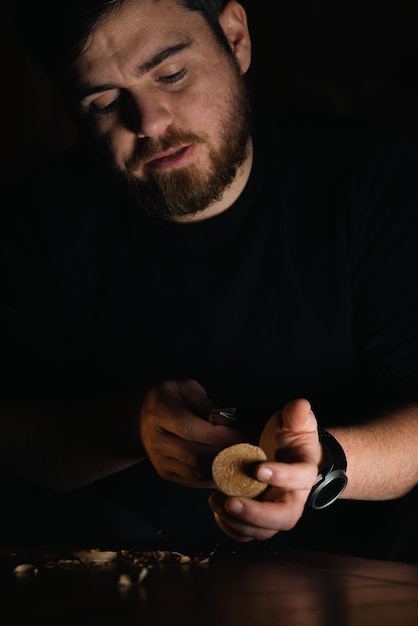 Male hands carve wood with a knife