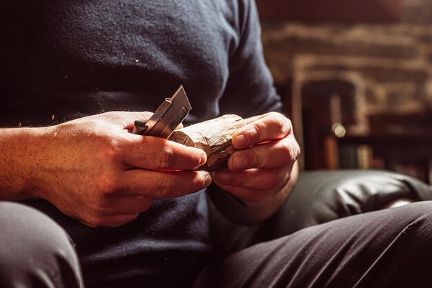 Male hands carve wood with a knife