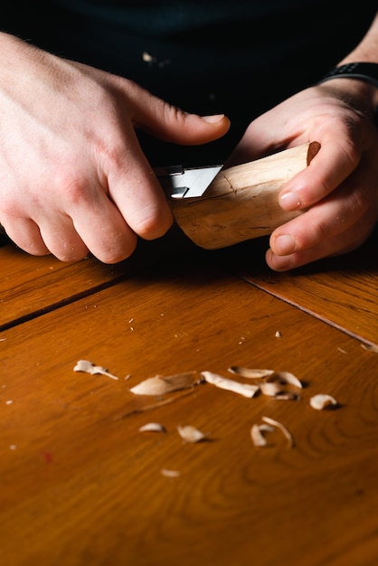 Male hands carve wood with a knife