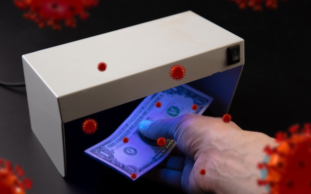 Male hands checking of banknotes in the detector 3D models of coronavirus spreding around