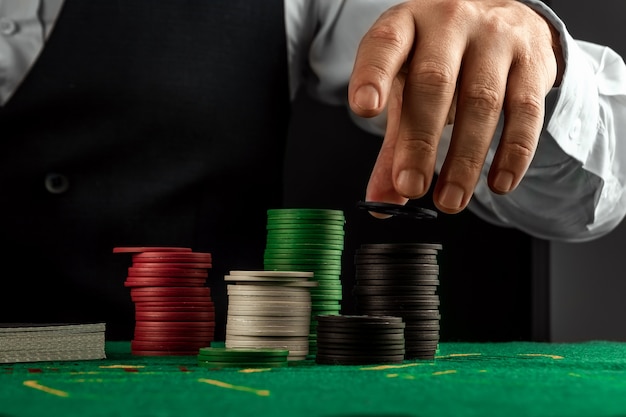 Male hands croupier in a casino and playing chips on a green cloth closeup