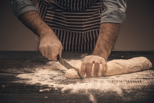 Male hands cut the dough