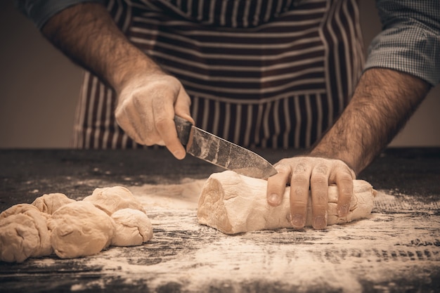 Male hands cut the dough