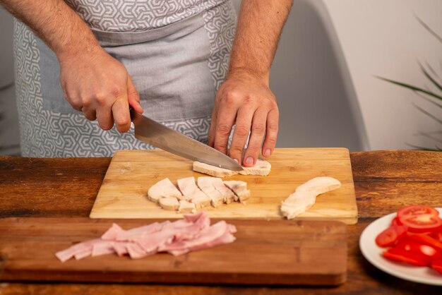 Male hands cutting ham on a board