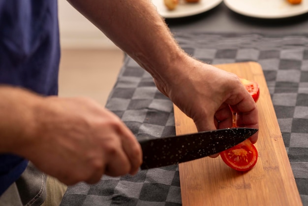 사진 남자 손 이 보드 에 토마토 를 자르고 있다