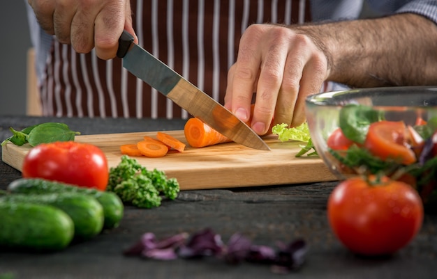 Photo male hands cutting vegetables for salad