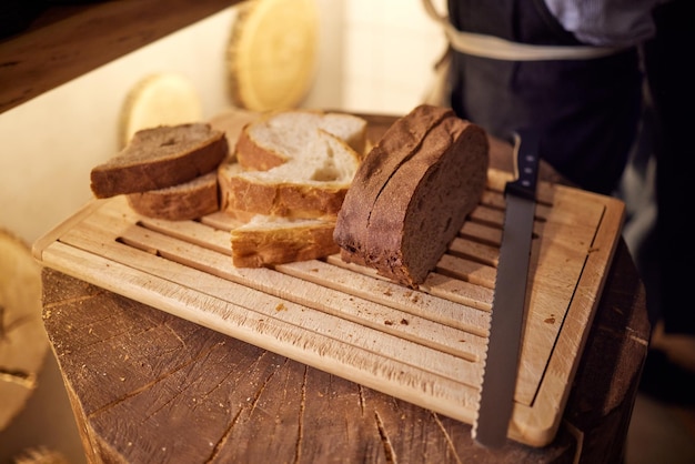 Male hands cutting wheaten bread on the wooden board, selective focus.