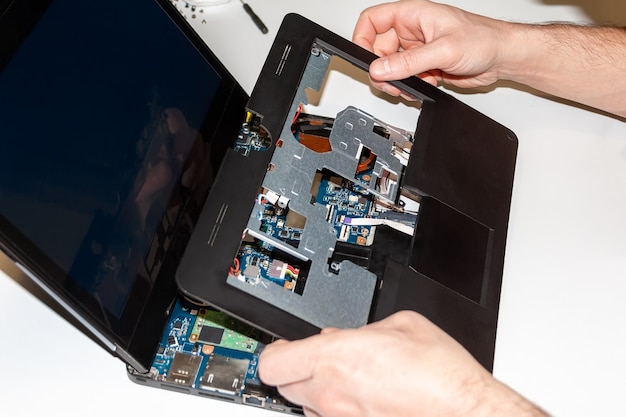 Male hands disassemble laptop for repair