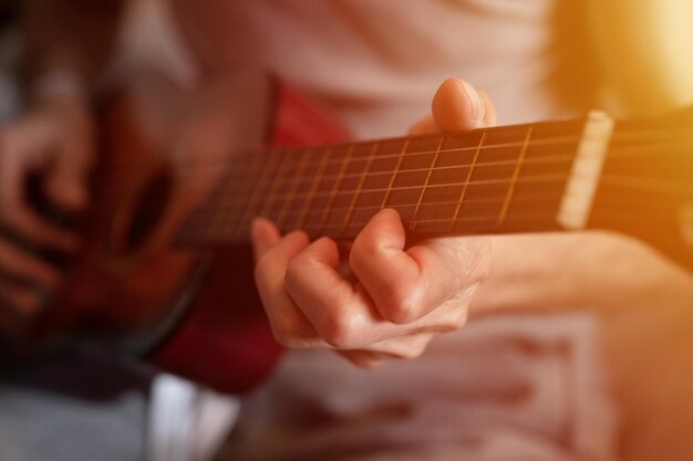 自宅でクラシック ギターを持って演奏する年配の白人男性の手のクローズ アップ