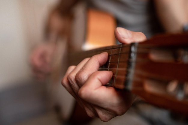 Male hands of an elderly senior caucasian man holding and\
playing a classical guitar close up at home unprofessional faceless\
guitarist people play amateur music domestic hobbies and\
leisure