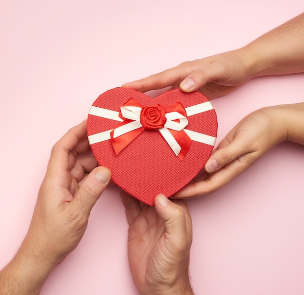 Male hands give a red box with a gift to a woman, top view