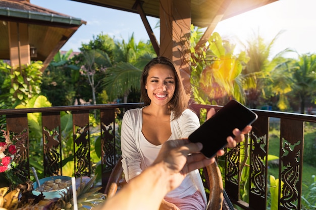 Mani maschii che danno allo smart phone delle cellule della donna con lo schermo in bianco vuoto