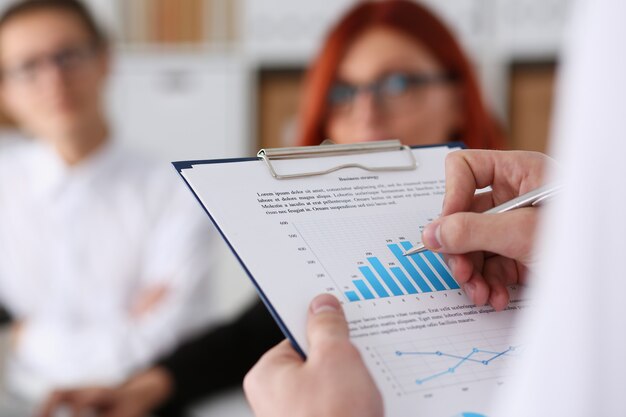 Male hands hold clipboard pad with statistics