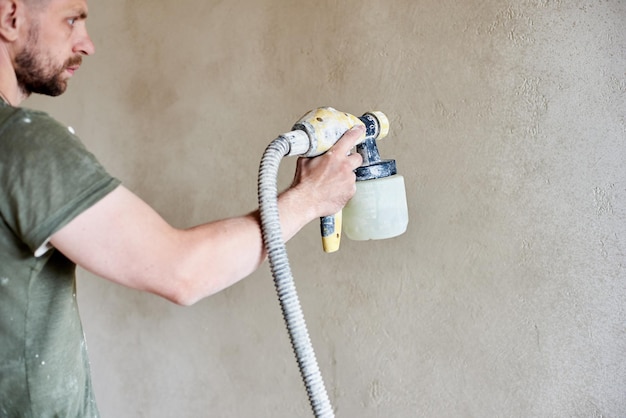 Le mani maschili tengono lo strumento la vernice spray rimodellare l'appartamento