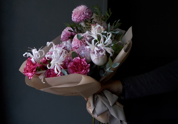 Male hands holding a bouquet decorated in vintage style on a dark background