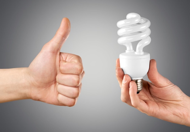 Male hands holding bulb lamp and showing thumbs up