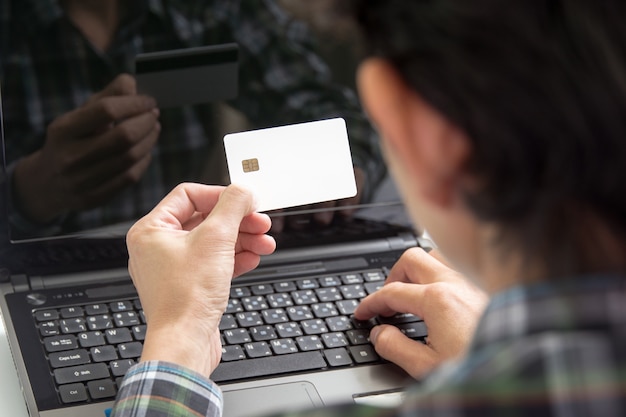 male hands holding credit card typing numbers on computer keyboard :online shopping concept