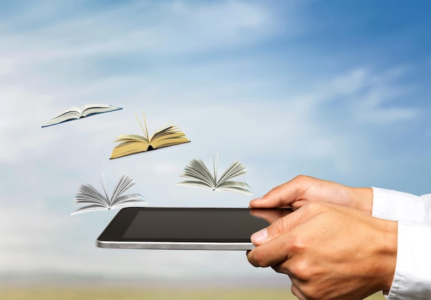 Male hands holding digital tablet near little flying books