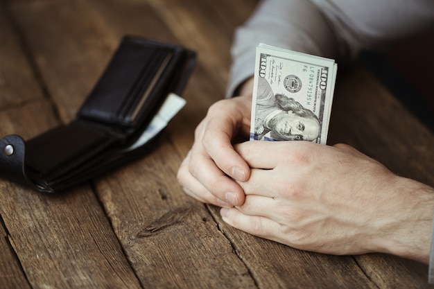 Foto mani maschii che tengono la banconota del dollaro sulla vecchia tavola di legno