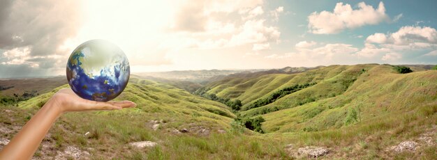 Foto mani maschii che tengono terra con sfondo di paesaggio