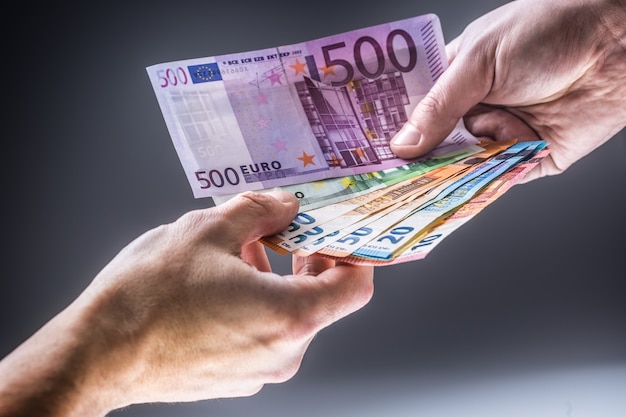 Male hands holding euro banknotes and the other hand to receive a bribe.