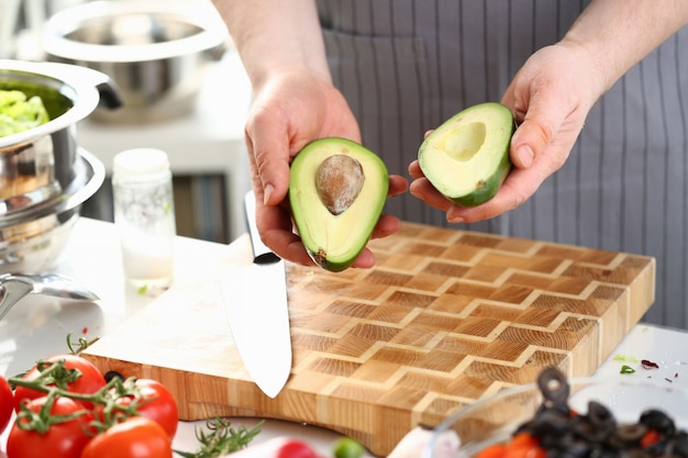 Mani maschii che tengono le metà verdi della frutta dell'avocado