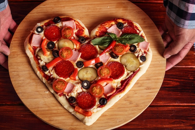 Photo male hands holding heart shapes pizza valentines day surprise gift concept