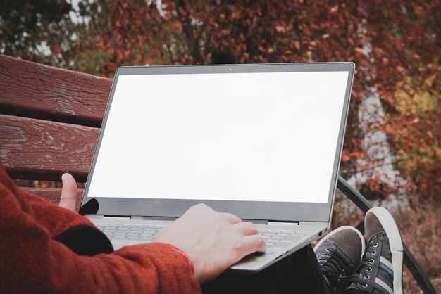 Male hands holding a laptop with a touch screen and pointing at a blank white screen Freelancer working outdoors in the Park