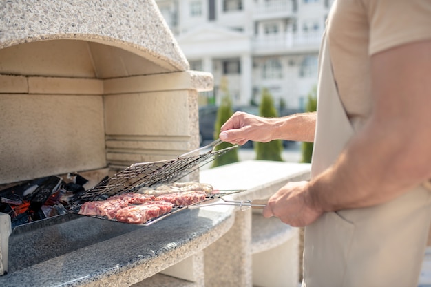 Male hands holding a meat grill