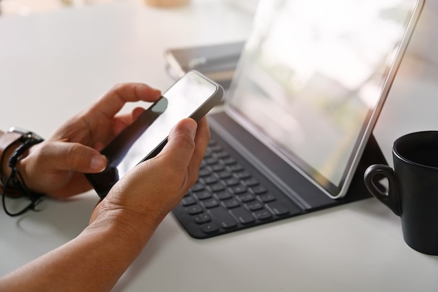 Male hands holding mobile smartphone on workplace  