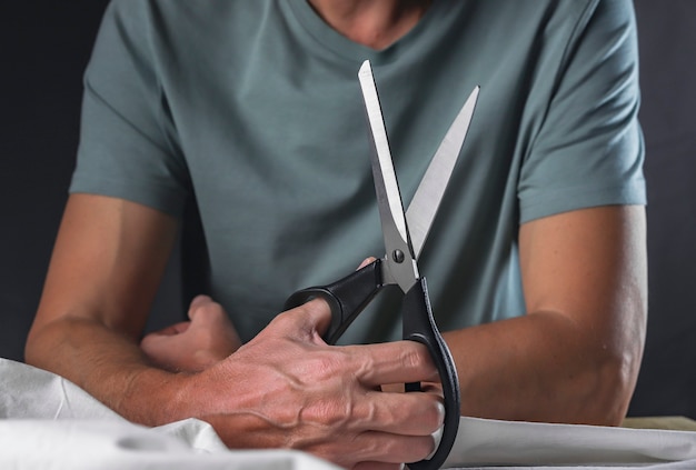 Male hands holding professional tailor sewing scissors.