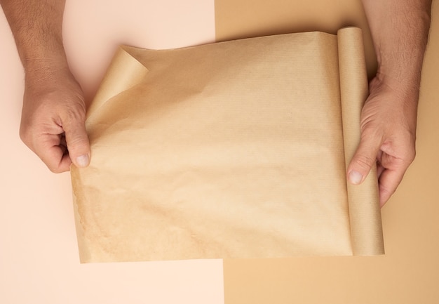 male hands holding a roll of brown paper