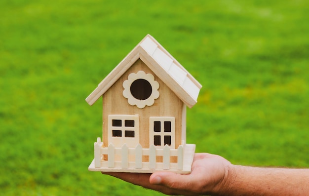 Male hands holding small miniature toy house mortgage property insurance dream moving home and real