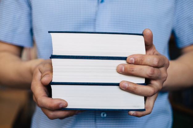 Male hands holding a stack of books.