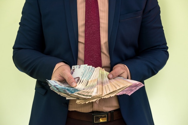 Male hands holding stack of ukrainian hryvnia banknotes isolated on green. Hryvnia new 1000 500 and 200 uah banknotes. Save money concept