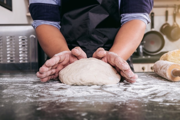 Male hands kneading dough sprinkled with flour table, Hands preparing bread