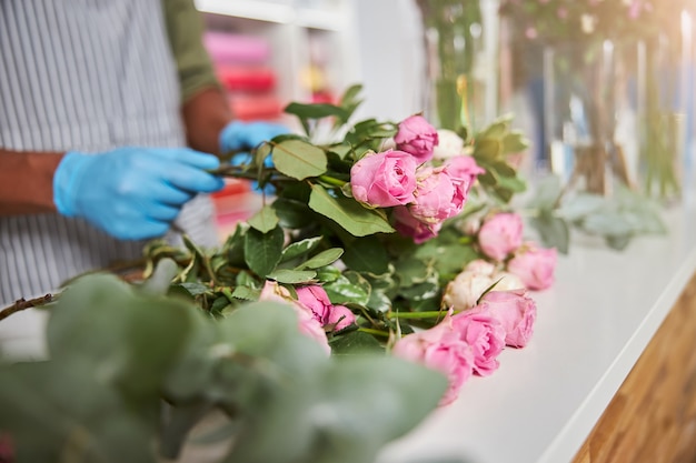 male hands in latex gloves while making bouquets of fresh flowers in shop